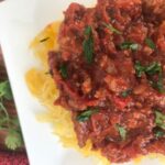 Meat sauce on top of spaghetti squash on a white plate-top view