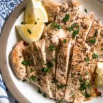 Top view of sliced grilled chicken breasts on a tan plate