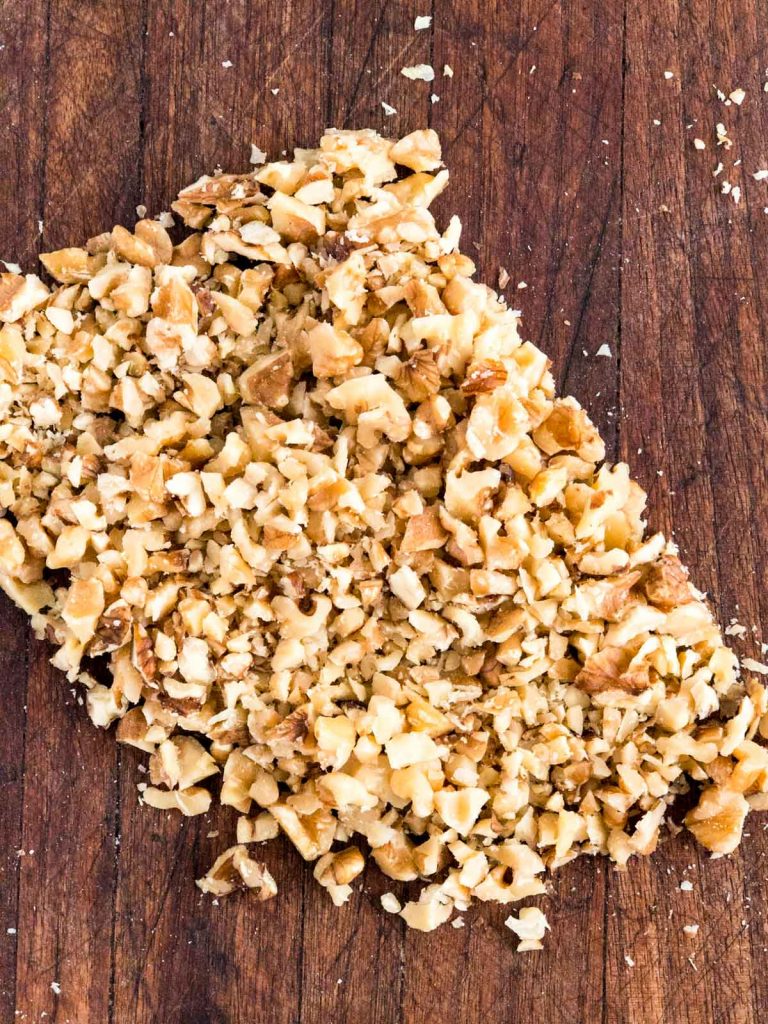 Rough chopped walnuts on a cutting board