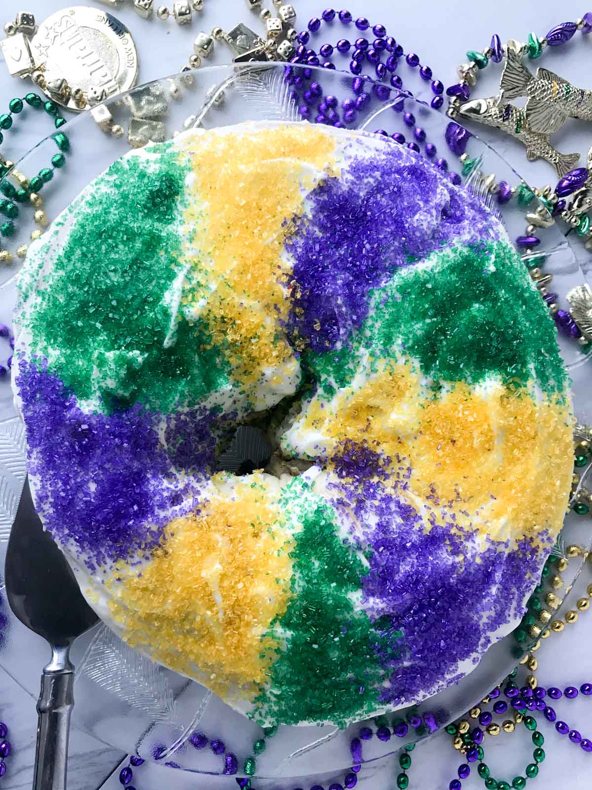 King cake with Mardi Gras beads surrounding it