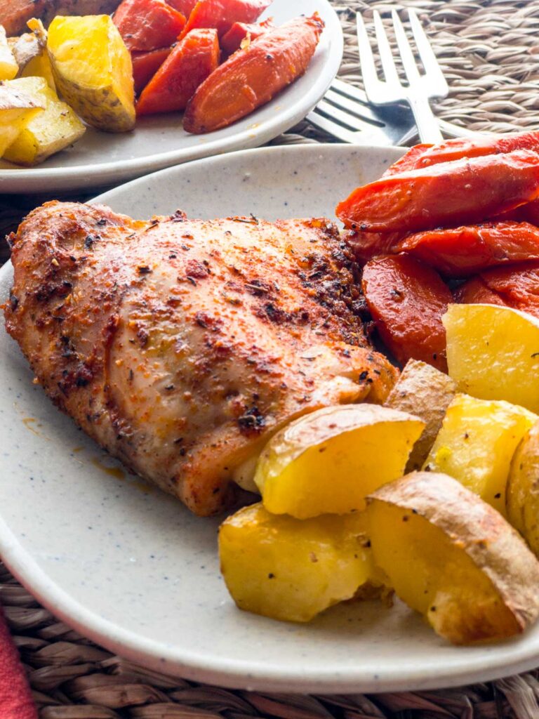 Sheet Meal: Spice baked chicken thigh with roasted carrots and potatoes on a plate