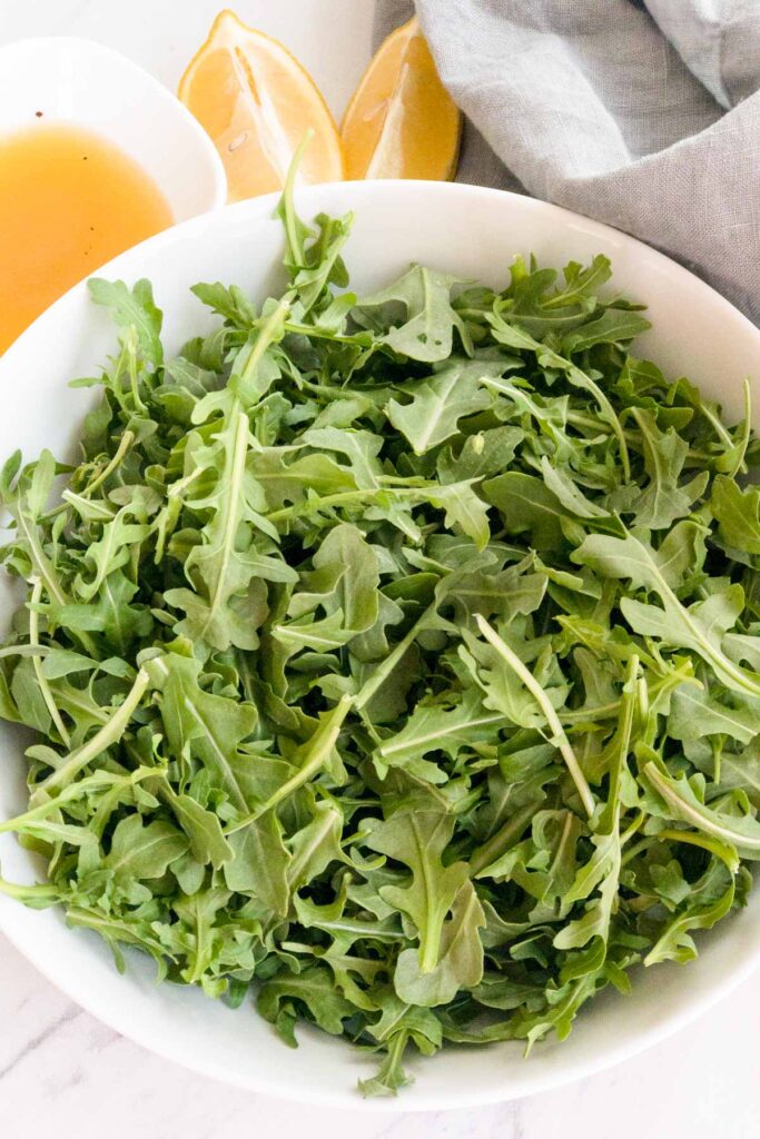 Baby arugula in a white bowl