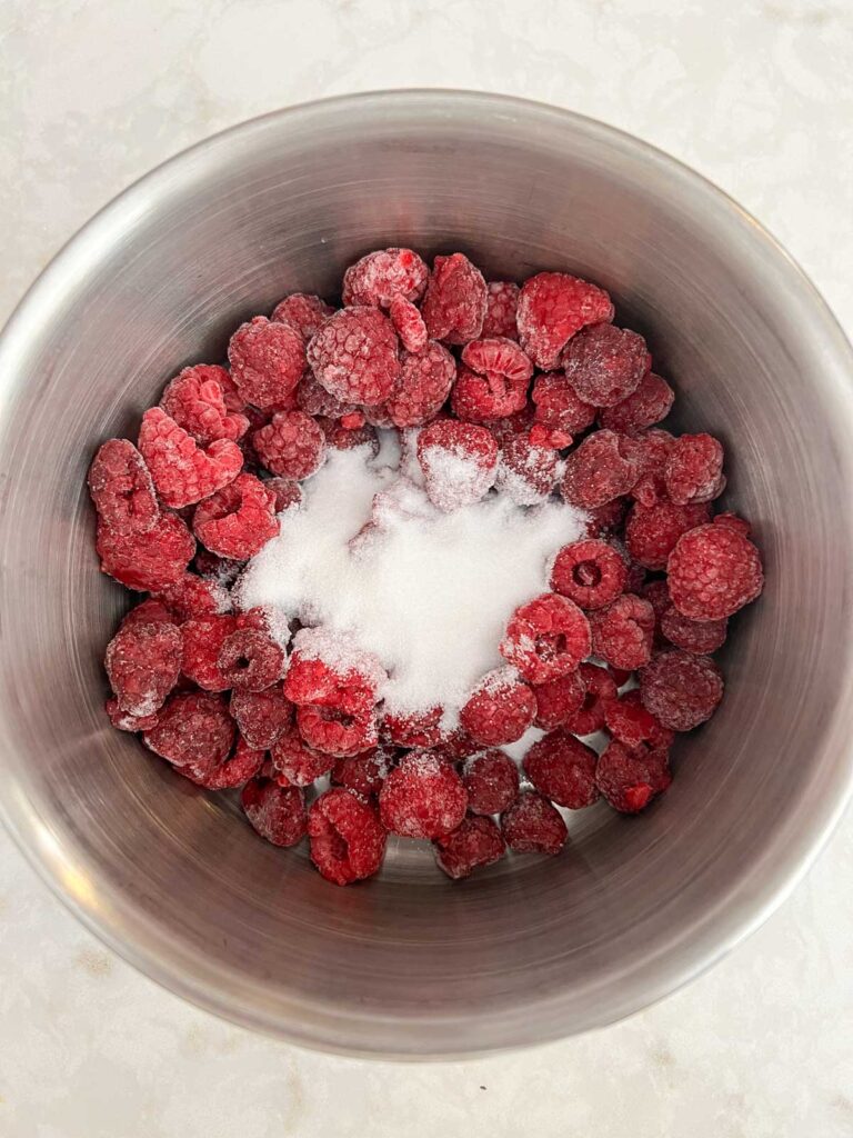 Sugar on top of frozen raspberries in a sauce pan