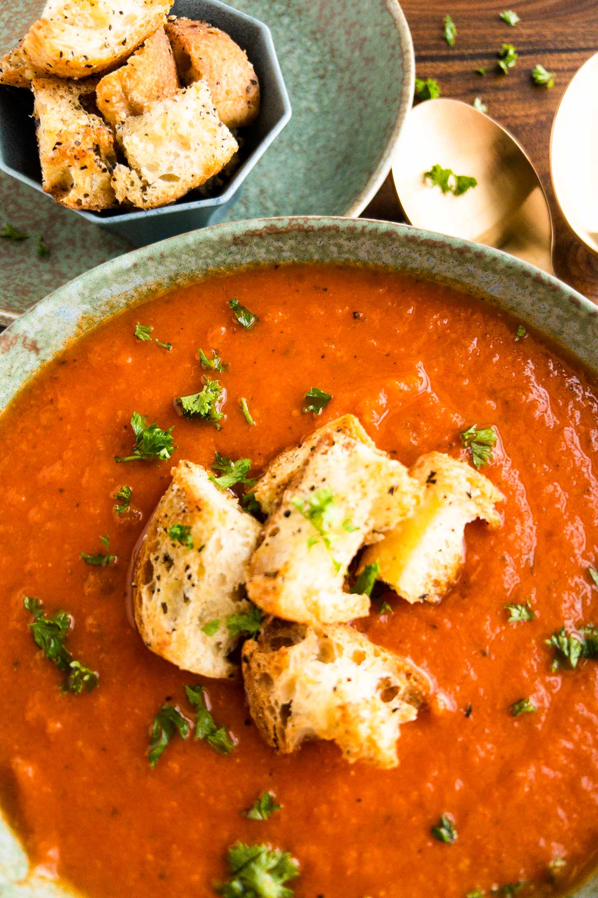 Tomato soup in a bowl garnished with croutons and parsley