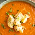 Tomato soup in a bowl garnished with parsley and croutons