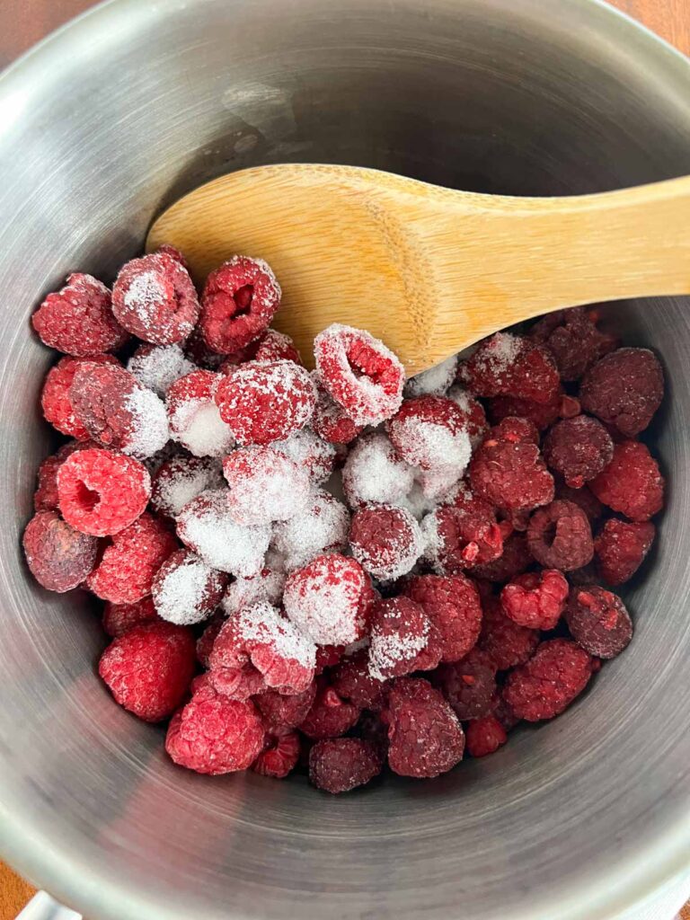 Raspberries and sugar in a sauce pan