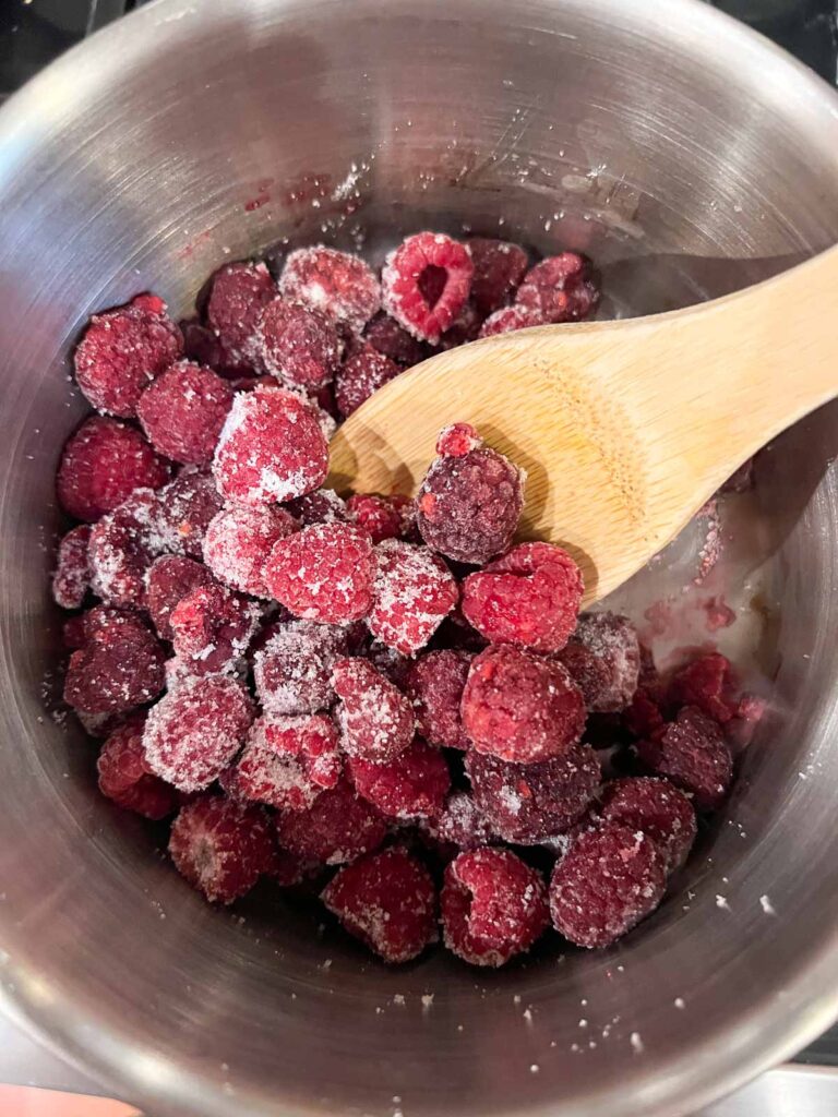 Sugar mixed with raspberries in a sauce pan