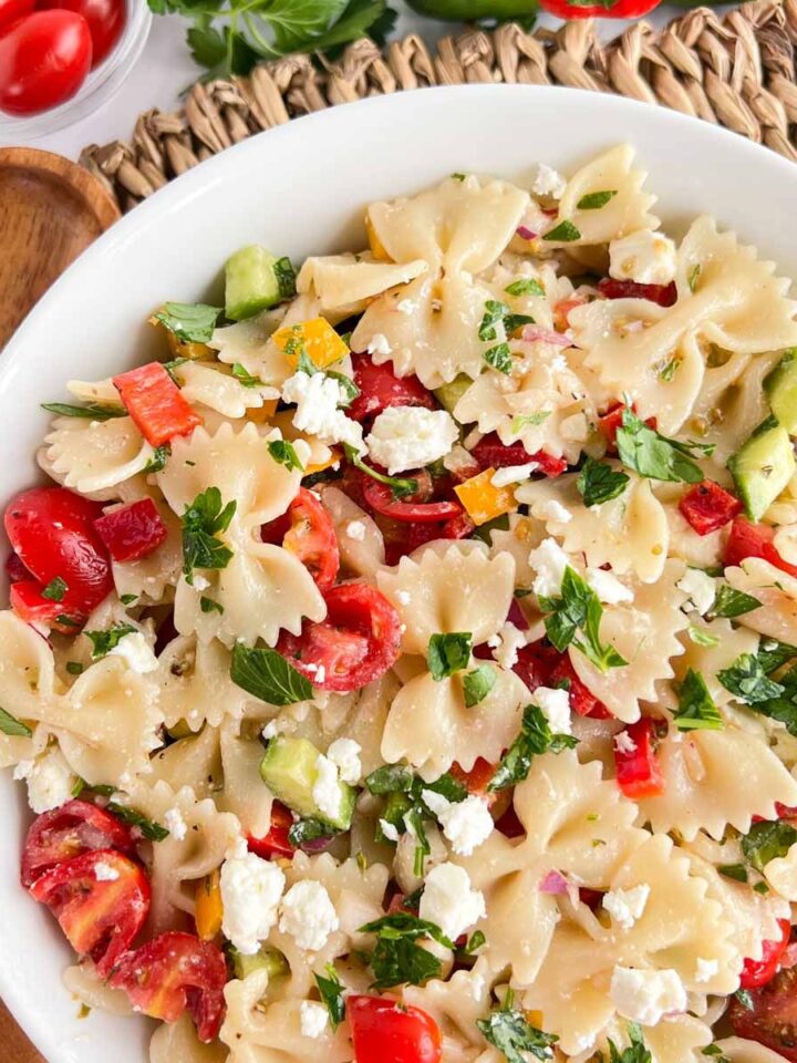 Greek pasta salad with farfalle pasta, grape tomatoes, cucumbers, feta cheese, parsley