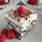 A piece of Chocolate Ice box cake with raspberries on a plate