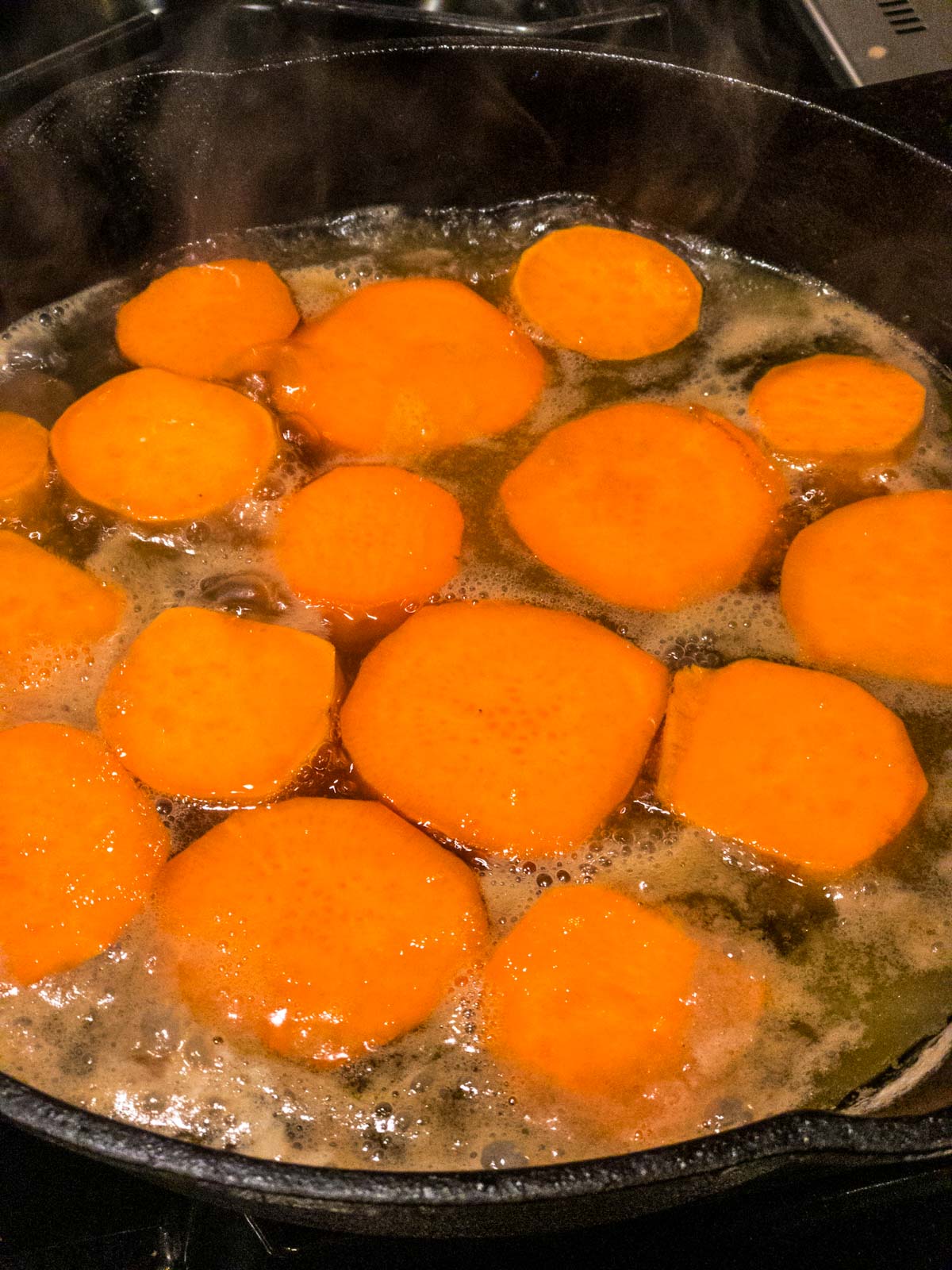 sweet potato rounds cooking in a cast-iron pan