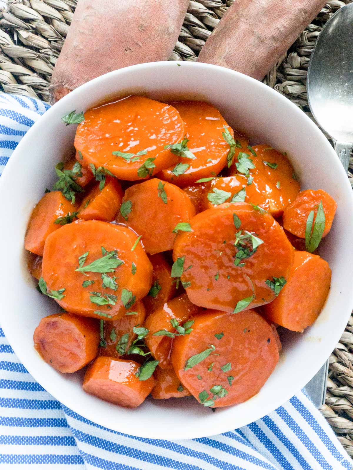 Glazed sweet potato slices garnished with parsley in a white bowl