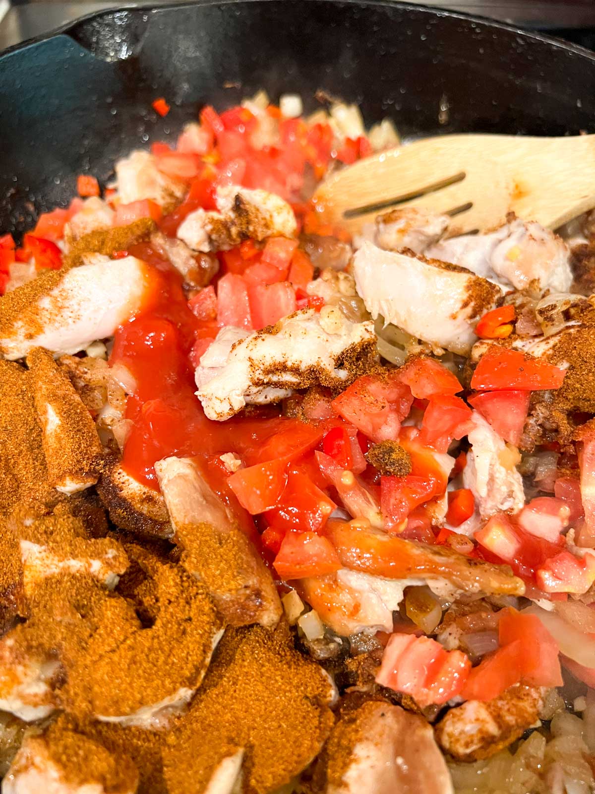 Browned chicken thigh pieces, onions, paprika, diced tomatoes and red peppers in a Dutch Oven