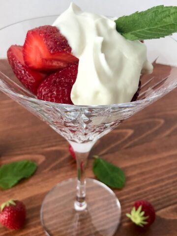 Fresh Strawberries with topping in a martini glass on a wood table