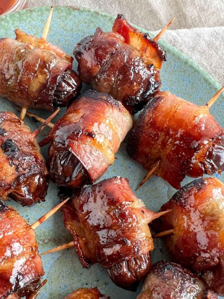 bacon wrapped dates with toothpicks through them on a blue plate