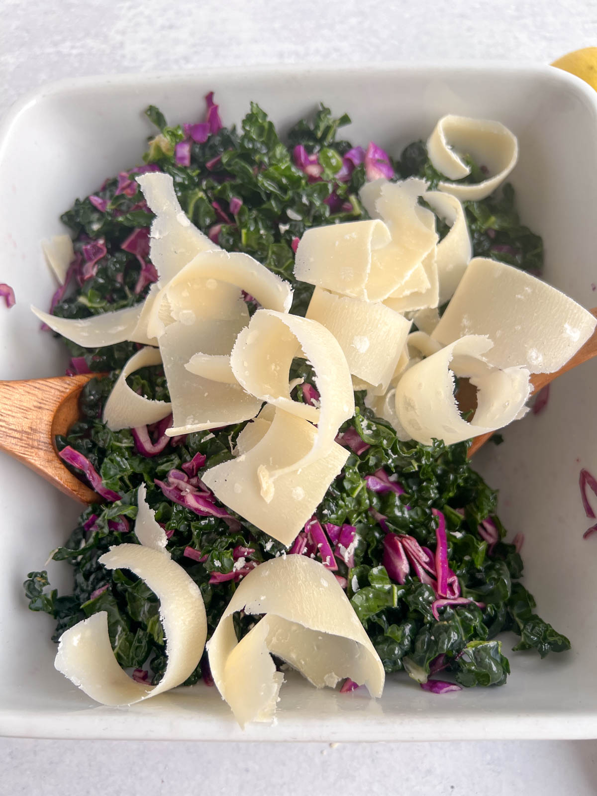 Parmesan shavings on kale and red cabbage in a white bowl 