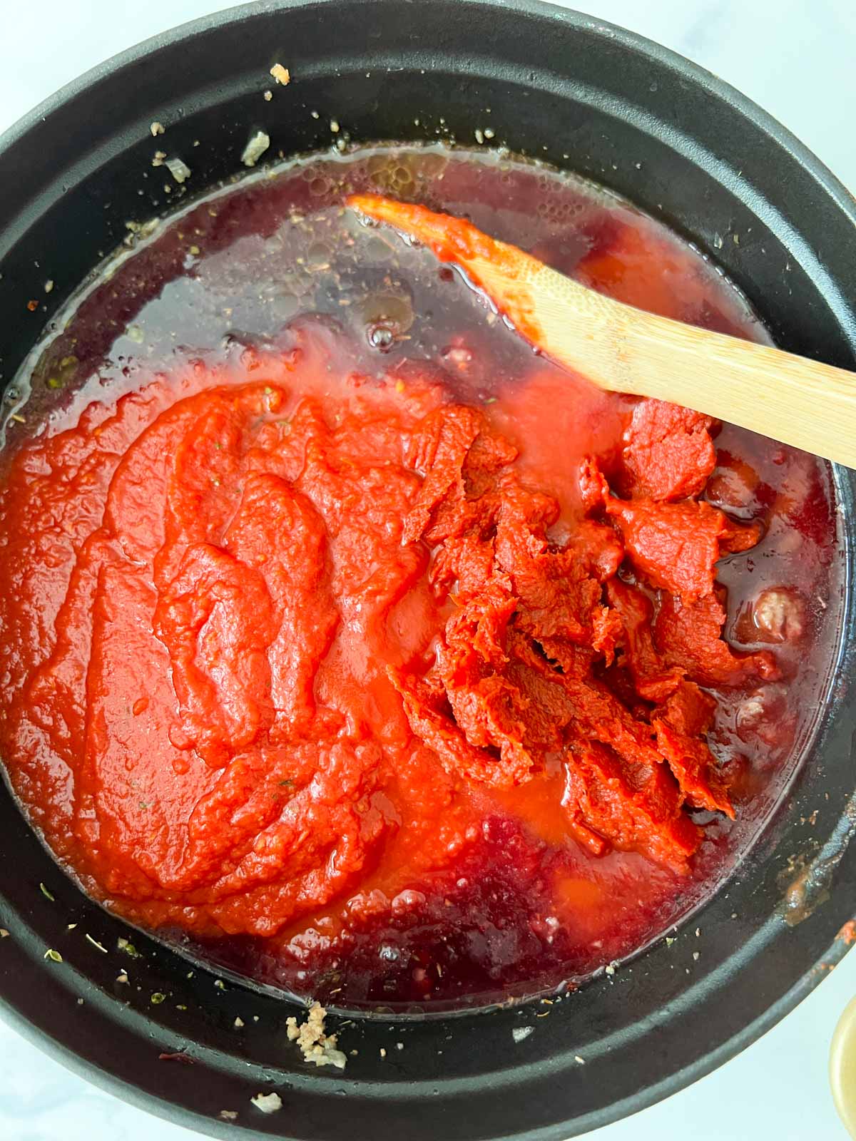 Crushed tomatoes, tomato sauce and tomato paste on top of cooked turkey meat in a dutch oven