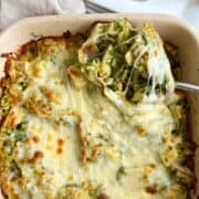 Serving spoon with chicken, orzo and pesto in a square baking casserole