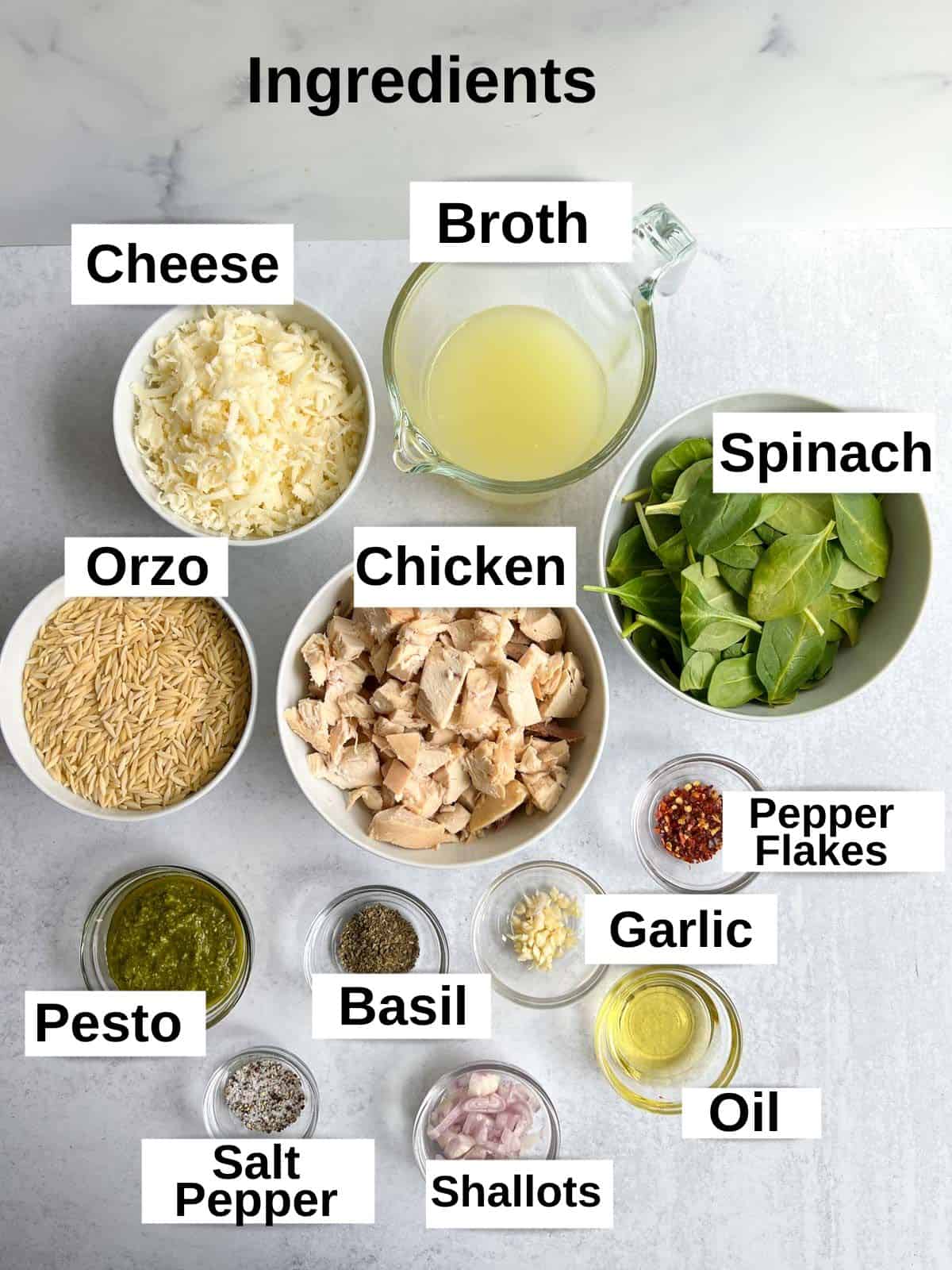 Ingredients for the chicken and pesto recipe each in individual bowls: Cooked chicken, broth, spinach, orzo, cheese, pesto, basil, garlic, pepper flakes, oil, garlic, salt and pepper