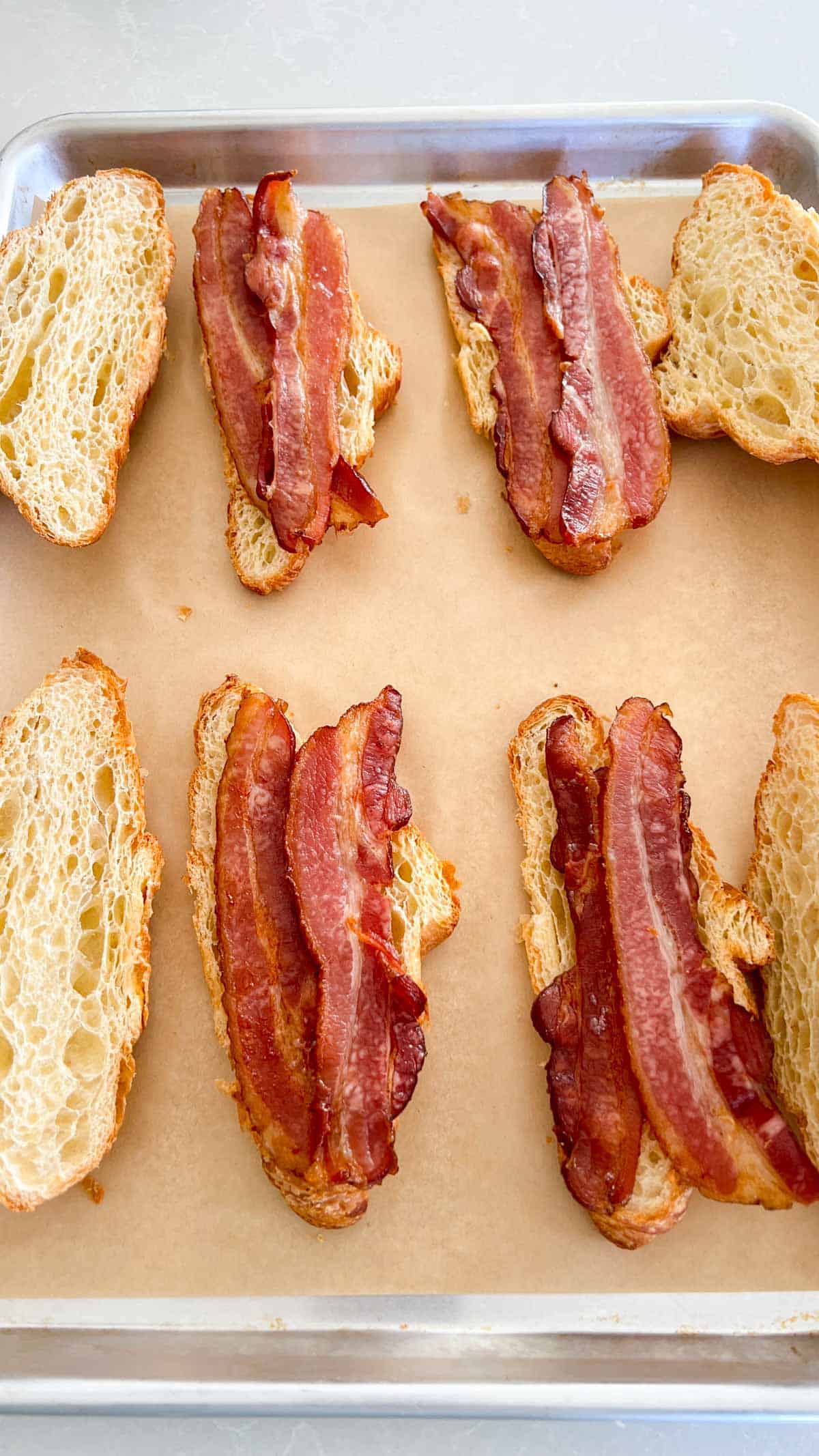 Croissant halves and bacon on bottom half of croissant