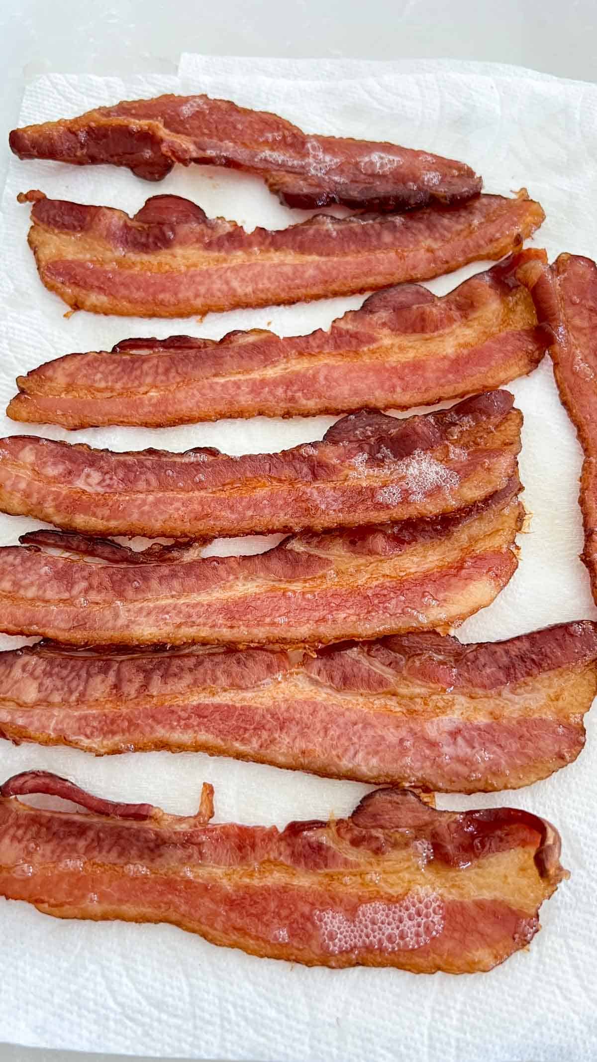 Cooked bacon draining on a paper towel