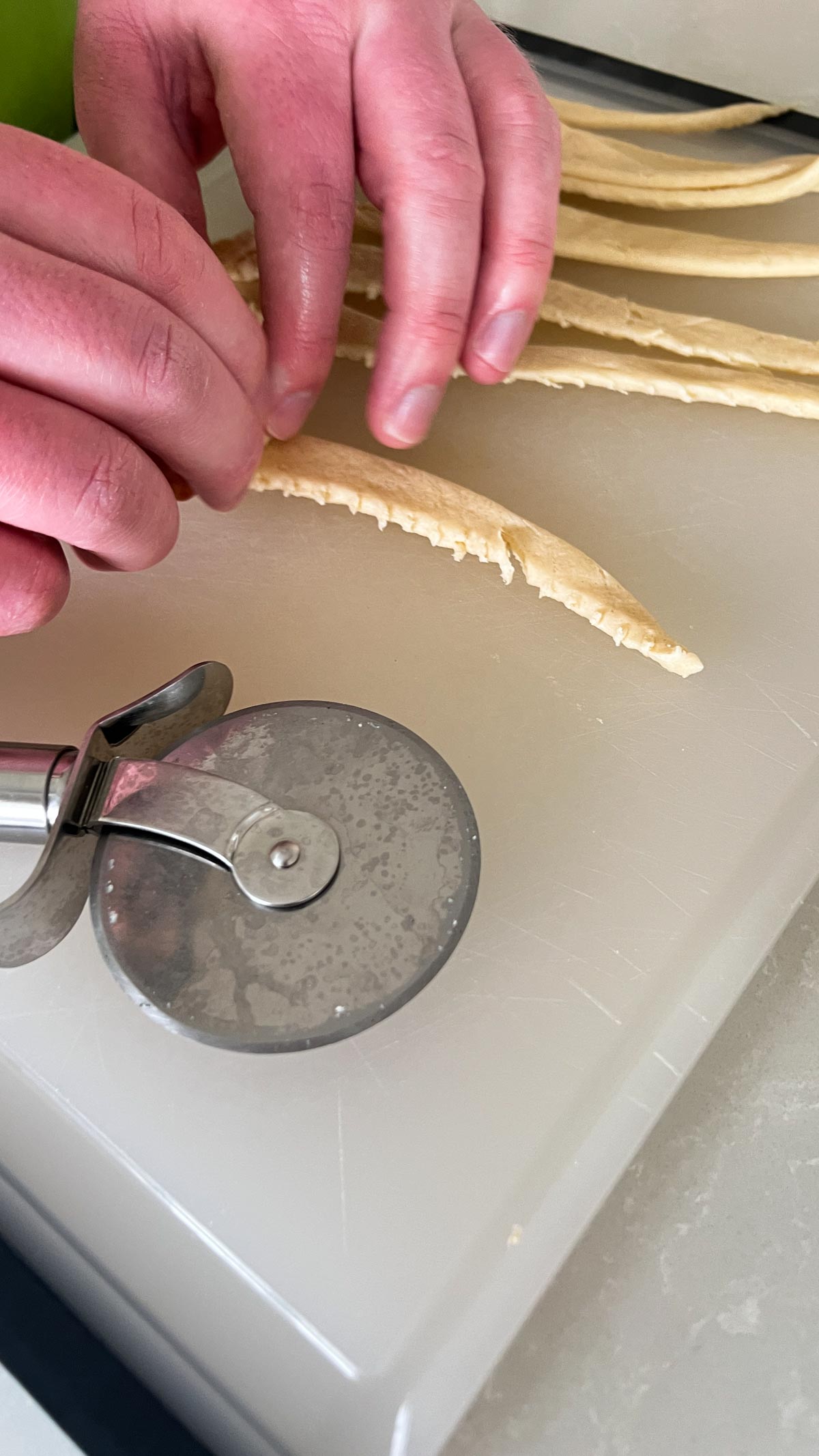 Hand rolling a mini sausage in a strip of crescent dough